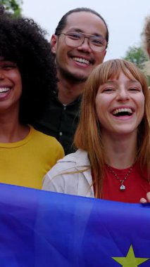 Avrupa Birliği Bayrağını tutan çeşitli insanların dikey HD videosu. Dışarıda kameraya gülümserken.