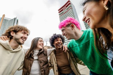 Çok ırklı bir grup genç arkadaş dışarıda gülüp eğleniyorlar. Milenyum kuşağı insanları, şehir caddesinde takılırken birbirlerini kucaklarken eğleniyorlar. Çeşitlilik ve topluluk