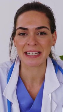 Klinikteki tıbbi konsültasyondan laptopta hastayla konuşan genç bayan doktorun dikey video görüntüsü. Sanal sağlık konferansı ve teletıp konsepti 