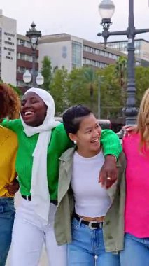 Açık havada birlikte yürüyen mutlu kadın arkadaş grubunun dikey HD videosu. Neşeli kızların birbirlerine sarılıp birlik ve beraberlik gösterdikleri kadın arkadaşlığı kavramı..