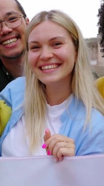 İtalyan bayrağını açık havada tutarken kameraya gülümseyen çeşitli gençlerin dikey HD videosu. Farklı milletlerden İtalyan vatandaşları birlik gösteriyor