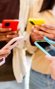 Dışarıda akıllı telefon kullanan bir grup öğrencinin dikey görüntüsü. Şehir caddesinde cep telefonu kullanan binlerce yıllık arkadaşlar..