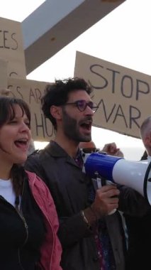 Dünya barışı için yürüyen bir grup aktivist insan. Çeşitli göstericiler savaş ve şiddeti protesto eden pankartlar ve posterler taşıyorlar. Savaş protestosu konsepti yok.