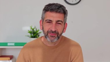 Yetişkin bir iş adamı iş yerinde kameraya gülümsüyor. İş adamları ve sanal konferans konsepti.