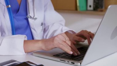 Dizüstü bilgisayarda çalışan kadın doktorların, profesyonel klinik ortamında dijital tıbbi kayıtlara ve hasta verilerine odaklanma