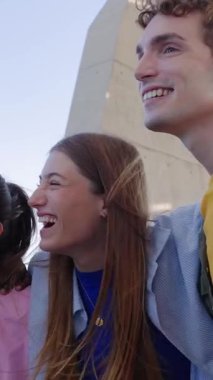 Güneşli bir günde dışarıda eğlenen genç insanların dikey HD videosu. Çok ırklı en iyi arkadaşlar birlikte vakit geçiriyorlar. Birleşik Milenyum öğrencileri gülüyor.