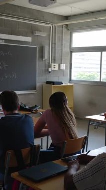 Üniversitede ya da okulda öğretmenlik yapan yetişkin bir kadının dikey HD videosu. Bayan öğretmen sınıftaki öğrencilerine bir ders veriyor. Lise ve ortaöğretim