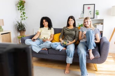 Üç bayan arkadaş bir kanepede dinleniyor, sağlıklı salatalarını yiyor ve modern dairelerinde televizyon programının keyfini çıkarıyorlar. Kadın arkadaşlığı ve gençlik kavramı