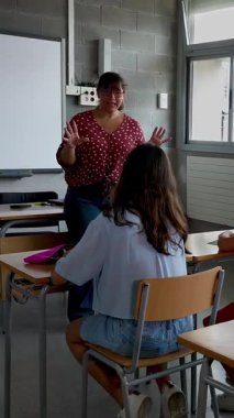 Genç bayan öğretmenin ilkokul öğrencilerine ders açıklarken çekilmiş dikey HD videosu. Eğitim yaşam tarzı kavramı