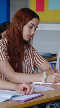 Lisedeki öğretmenleri dinlerken not alan genç bir kızın dikey HD videosu. Üniversitede çeşitli insanlar okuyor. Eğitim yaşam tarzı kavramı.