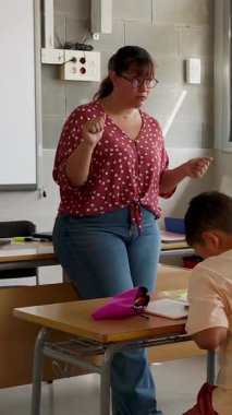 Genç bayan öğretmen sınıftaki ilkokul öğrencilerine ders anlatıyor. Eğitim yaşam tarzı kavramı