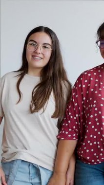 İlkokulda sınıfta duran iki genç kız öğrenciyle birlikte mutlu bayan öğretmenin dikey HD video portresi.