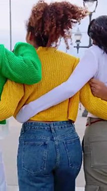 Dikey HD video. Genç bir grup kadının arka planda birlikte yürümeleri açık havada kucaklaşmaları. Şehir caddesinde birbirine sarılan bayan arkadaşlar. Arkadaşlık ve kadın toplumu kavramı.