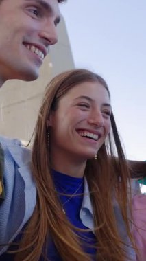 Açık havada birbirini kucaklayan melez gençlerin dikey HD videosu. Öğrenci genç arkadaşlar dışarıda takılırken gülüyorlar. Gençlik toplumu kavramı.