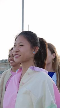 Dışarıda kaynaşan mutlu genç bir grup insanın dikey HD videosu. Mutlu bin yıllık öğrenci arkadaşlar birbirlerine sarılıyorlar. Şehir caddesinde yan yana duruyorlar. Gençlik toplumu kavramı.