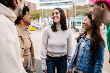 Dışarıda birlikte oturan bir grup genç insan cep telefonu kullanıyor. Çok ırklı mutlu arkadaşlar eğleniyor ve dışarıda gülüyorlar. Arkadaşlık ve gençlik toplumu kavramı