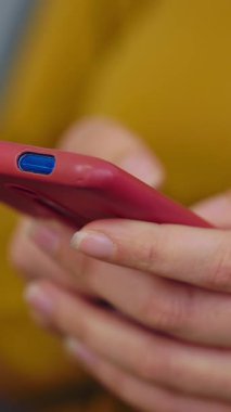 Dikey HD video. Genç bir kadının cep telefonuyla online mesaj yazışına, internete göz atmasına, sosyal medya için akıllı telefon uygulaması kullanmasına yakından bakın. Teknoloji konsepti