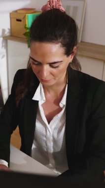 Parlak ofiste çalışan genç ve mutlu girişimci bir kadının dikey HD videosu. İş ve güçlendirme kavramı