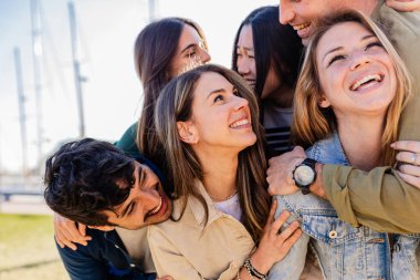 Çeşitli yetişkin arkadaş grupları dışarıda birbirlerine sarılırken eğleniyorlar. Neşeli milenyum insanları birlikte eğlenerek gülüyor. Topluluk ve arkadaşlık kavramı