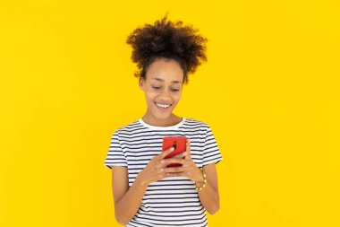 Sarı stüdyo üzerinden telefon kullanan mutlu Afrikalı kadın.