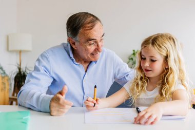 Küçük kız evde büyükbabasıyla ödev yapıyor. Eğitim kavramı