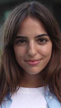 Dışarıda kameraya gülümseyen mutlu yetişkin güzel bir kadının dikey HD video portresi.