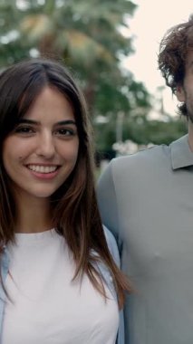 Dışarıda kameraya gülümseyen üç çok ırklı genç arkadaşın dikey HD videosu. Neşeli milenyum insanları yaz aylarında birbirlerine sarılıyorlar. Çeşitlilik ve insanlar kavramı