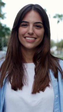 Dikey HD video. Kendinden emin gülümseyen yetişkin bir kadının yazın sokakta yürürken kameraya bakışının ön görüntüsü. Milenyum halkı ve gençlik kavramı