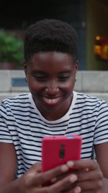 Genç ve mutlu öğrenci arkadaşlarının cep telefonundan komik videolar izleyerek güldükleri dikey HD videolar. Milenyum insan nesli dışarıdaki akıllı telefon cihazlarına göz atarak eğleniyor..