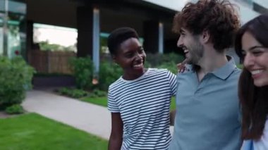 Üç farklı arkadaştan oluşan genç bir grup dışarıda gülerken birbirlerine sarılıyorlar. Milenyum kuşağı insanları yaz tatilinde eğleniyor..