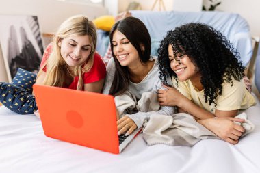 Üç neşeli, çok ırklı bayan arkadaş yatağında pijama partilerinin tadını çıkarıyor, dizüstü bilgisayar kullanıyorlar ve eğleniyorlar. Kadın arkadaşlığı ve gençlik kavramı