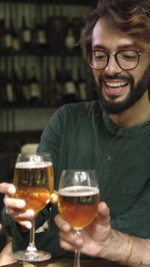 Bira fabrikası barında bira içen mutlu çok ırklı arkadaşların dikey HD videosu. Çeşitli gençler birlikte kutlama yapıyorlar İrlanda barında içkilerle tezahürat yapıyorlar, mutlu saatler geçiriyorlar.. 