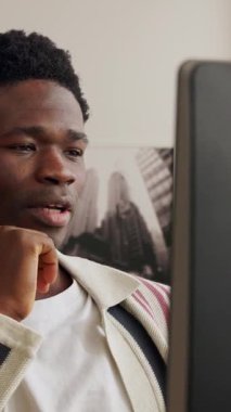 Ana ofisten bilgisayar kullanarak çalışan ve video konferansı yapan genç Afrikalı bir adamın dikey HD videosu. Eğitim, iş ve e-öğrenim kavramı