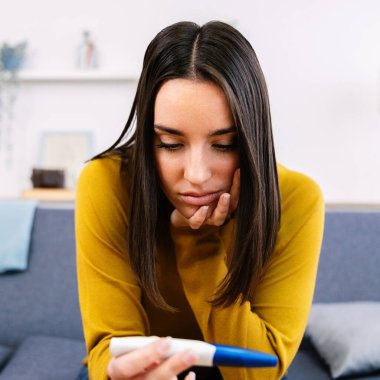 Şok olmuş genç ve güzel bir kadının hamilelik testi pozitif çıktı. İstenmeyen hamilelik kavramı.