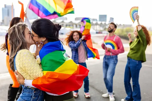Lezbiyen çift LGBTQ geçit töreninde öpüşüyor. Birbirine aşık iki genç kız arkadaş. Eşcinsel ve lezbiyen topluluğunun çeşitli insanları lgbt onur gününü kutluyorlar.