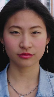 Dışarıda kameraya gülümseyen Asyalı genç kızın dikey HD video portresi. Bin yıllık mutlu Çinli kadın portresi pozitif hissediyor. Halk konsepti