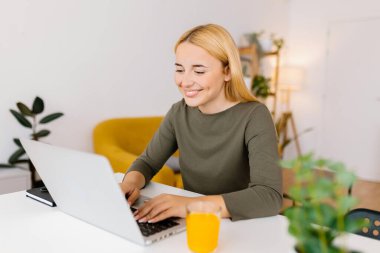 Evde dizüstü bilgisayar kullanan genç bir kadın öğrenci. Milenyum Kafkasyalı kadın öğrenimi çevrimiçi. İş ve eğitim kavramı.