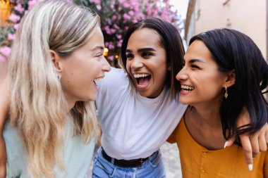 Açık havada birlikte gülen üç farklı genç kadın. Kadın arkadaşlığı ve yaz tatili yaşam tarzı konsepti