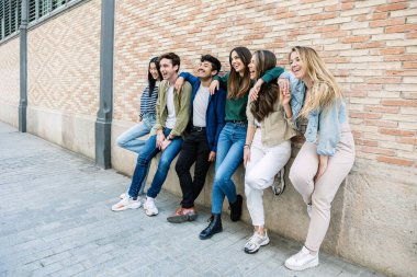 Young group of student people leaning against a brick wall. Youth community and friendship concept