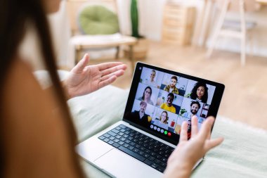 İş kadını, dizüstü bilgisayarında ekibiyle video konferansı düzenlerken evden uzaktan çalışıyor.