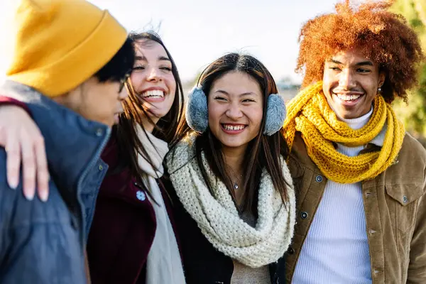 Young diverse gen z friends having fun together at city street on winter. Youth community and friendship concept