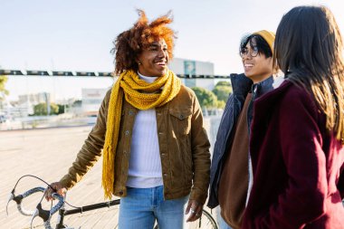 Young diverse group of friends hanging out together on winter walking at city street