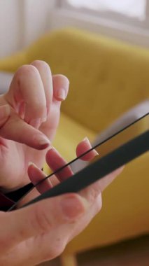 Vertical HD video. Close up of unrecognizable woman using mobile phone touchscreen at home. Social media and communication concept