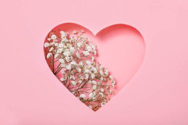 Pembe arka planda beyaz çiçekli bir kalp. Kalbin içinde çiçekler. Kartpostal, 8 Mart, Sevgililer Günü, Kadınlar Günü. Yakın plan..