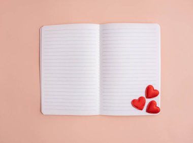 Notebook with hearts on a light background. Valentine's Day. Greeting card. Flat lay, top view. Copy space.
