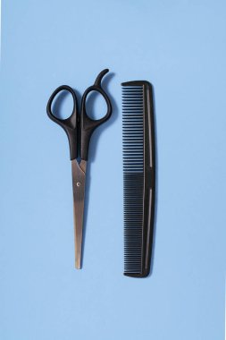 Hairdressing scissors and a comb on a blue background. The concept of a hairdresser, beauty salon, tools. Close-up. View from above.
