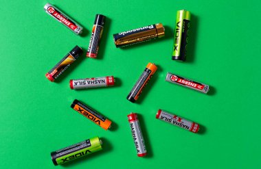 Kremenchuk, Ukrayna, 18 Mart 2023. Yeşil arka planda bir yığın farklı kullanılmış pil..