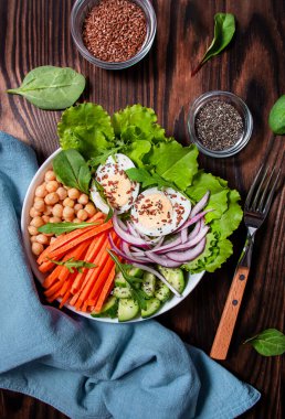 Haşlanmış yumurta, nohut, marul, taze havuç ve keten ve chia çekirdeği serpiştirilmiş salatalık. Keto diyeti. Süper yemek. Yukarıdan bak. Ahşap arkaplan.