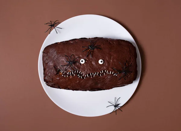 Halloween food. Scary chocolate cake with eyes and spiders on a light background. Terrible food. Thematic food. Halloween background. Copy space.