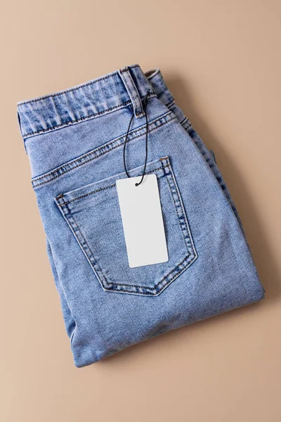Niebieskie Dżinsy Papierową Etykietą Beżowym Tle Wyprzedaż Ubrań Black Friday — Zdjęcie stockowe